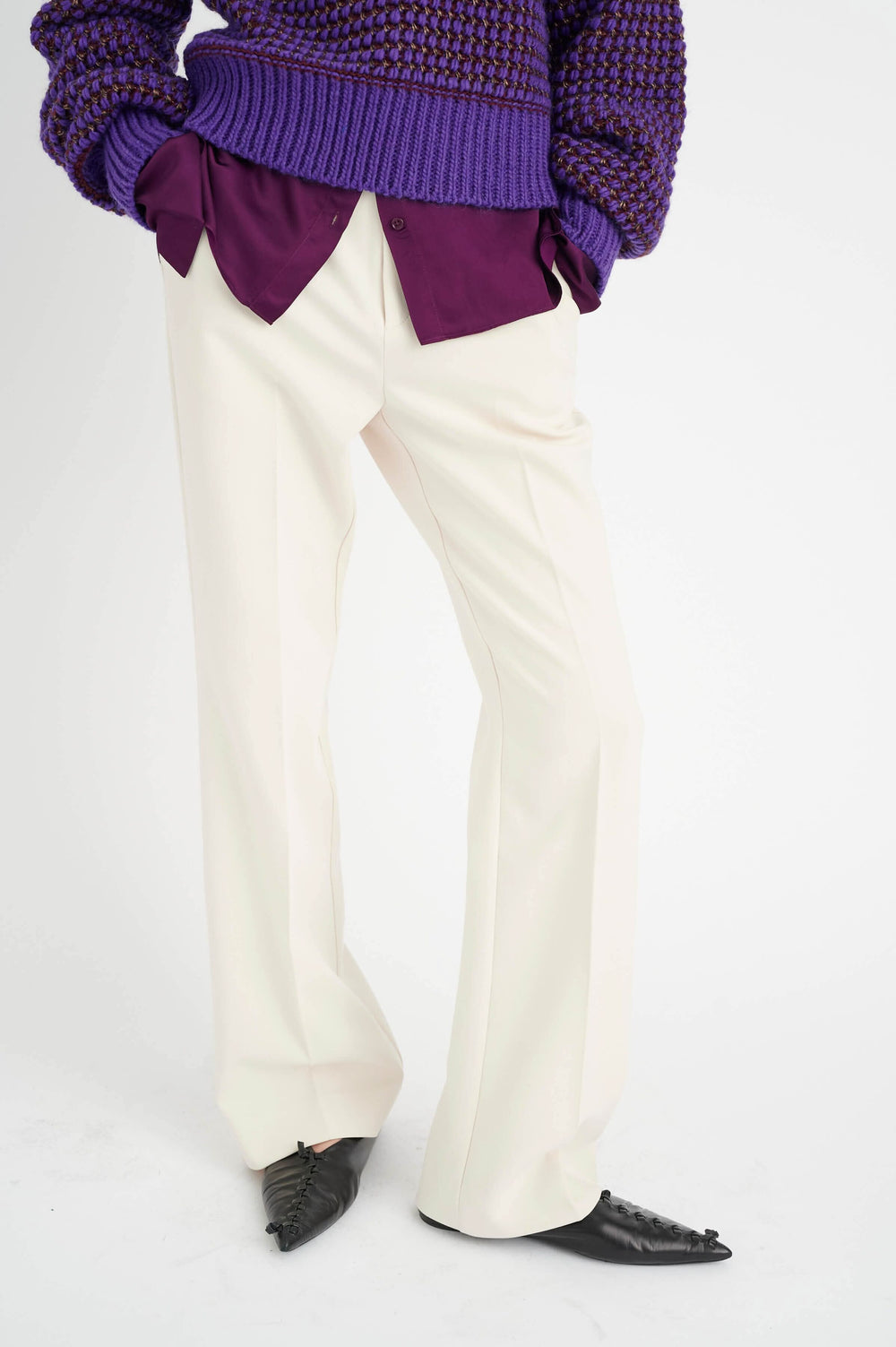 Pantalon Ibbie beige à jambe droite, porté avec un pull violet et une chemise bordeaux, vue latérale.