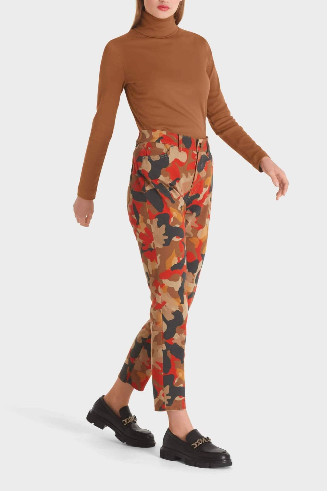 Femme portant un pantalon camouflage coloré et un pull à col montant, style moderne et attractif.