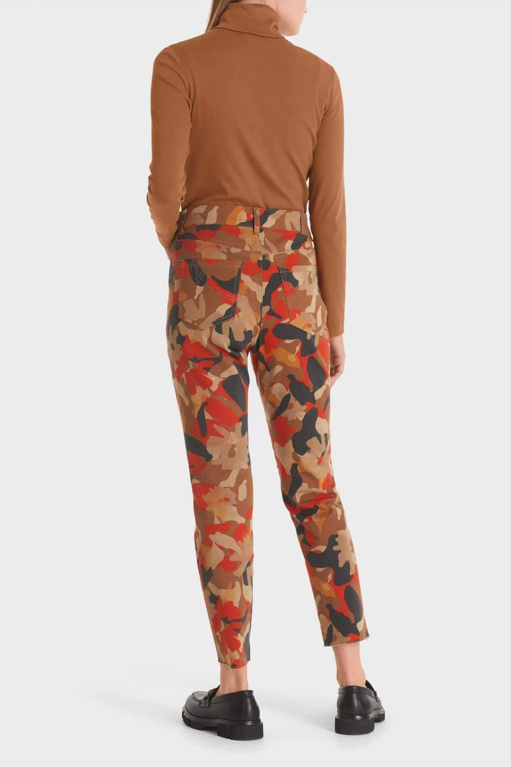 Femme vue arrière portant un pantalon imprimé camouflage en coton biologique couleur tangerine.