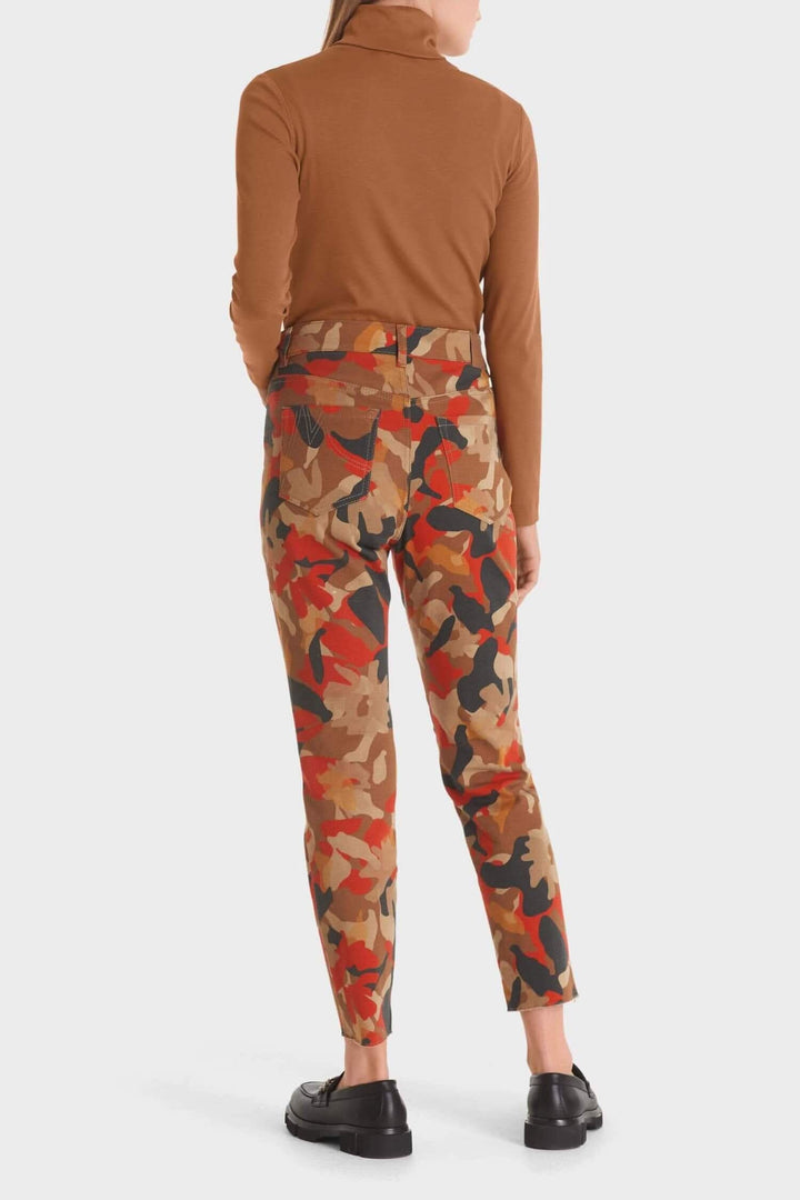 Femme vue arrière portant un pantalon imprimé camouflage en coton biologique couleur tangerine.