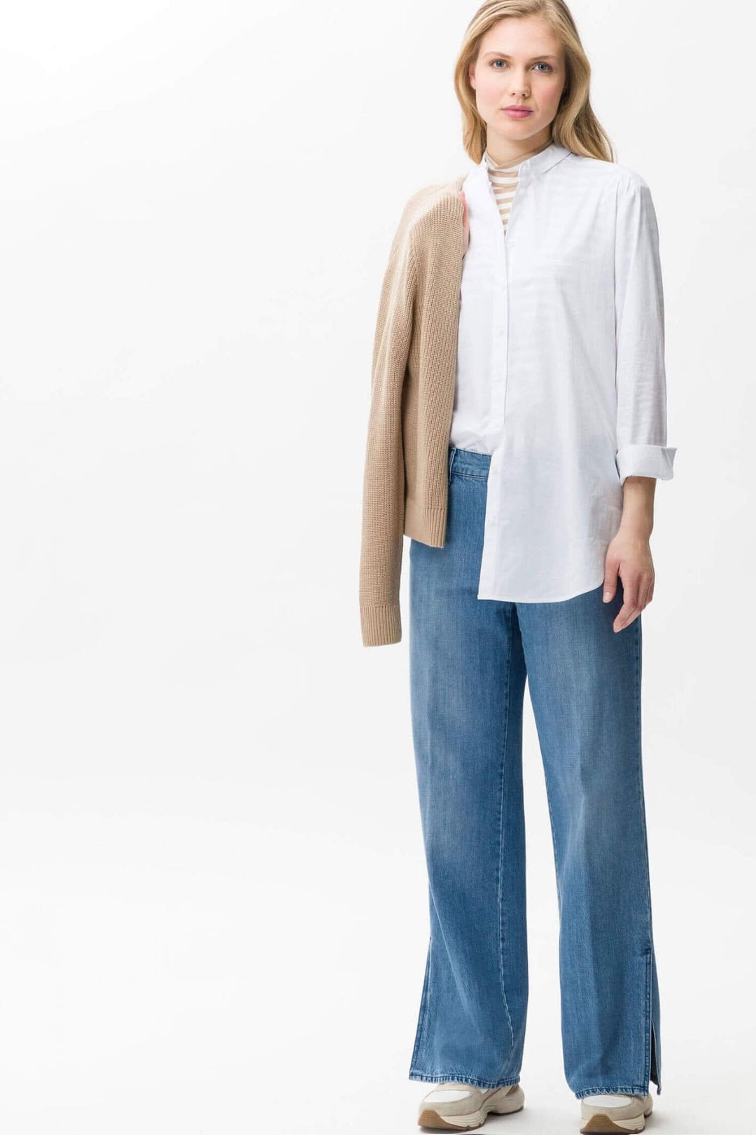 Femme portant un pantalon large Maine avec une chemise blanche et un cardigan, créant un look décontracté élégant.