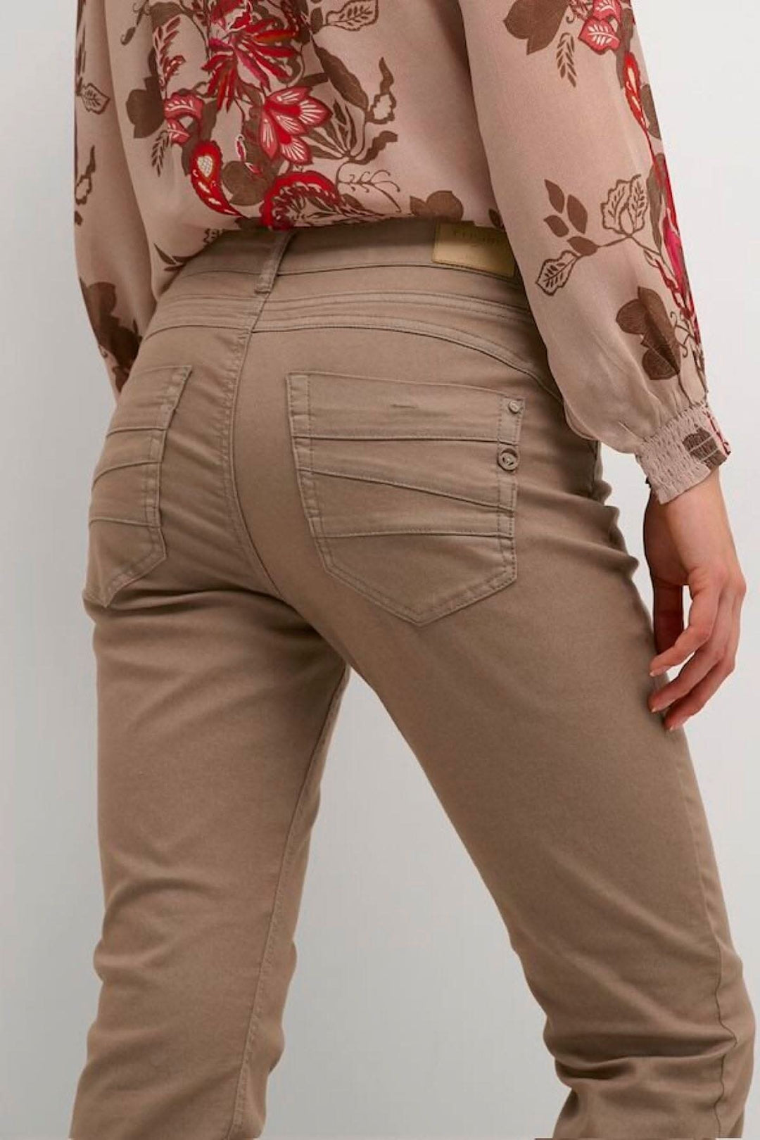 Femme portant un pantalon style jean étroit beige de dos, vue sur les poches et la coupe régulière.