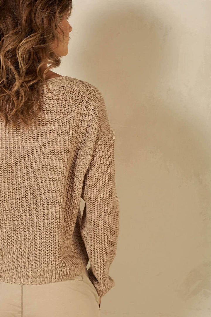 Pull à mailles en coton beige, col en v, vue arrière, maniques légèrement tombantes, style décontracté.