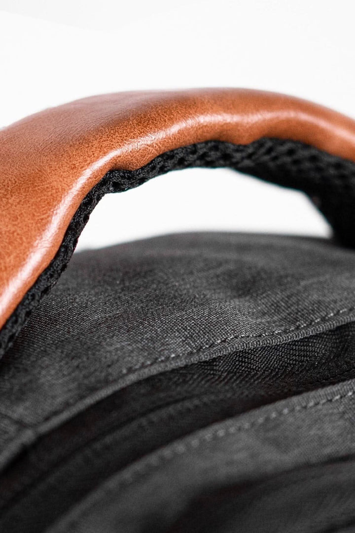 Détail du sac à dos PKG Durham avec une poignée en cuir marron et tissu noir résistant aux intempéries.