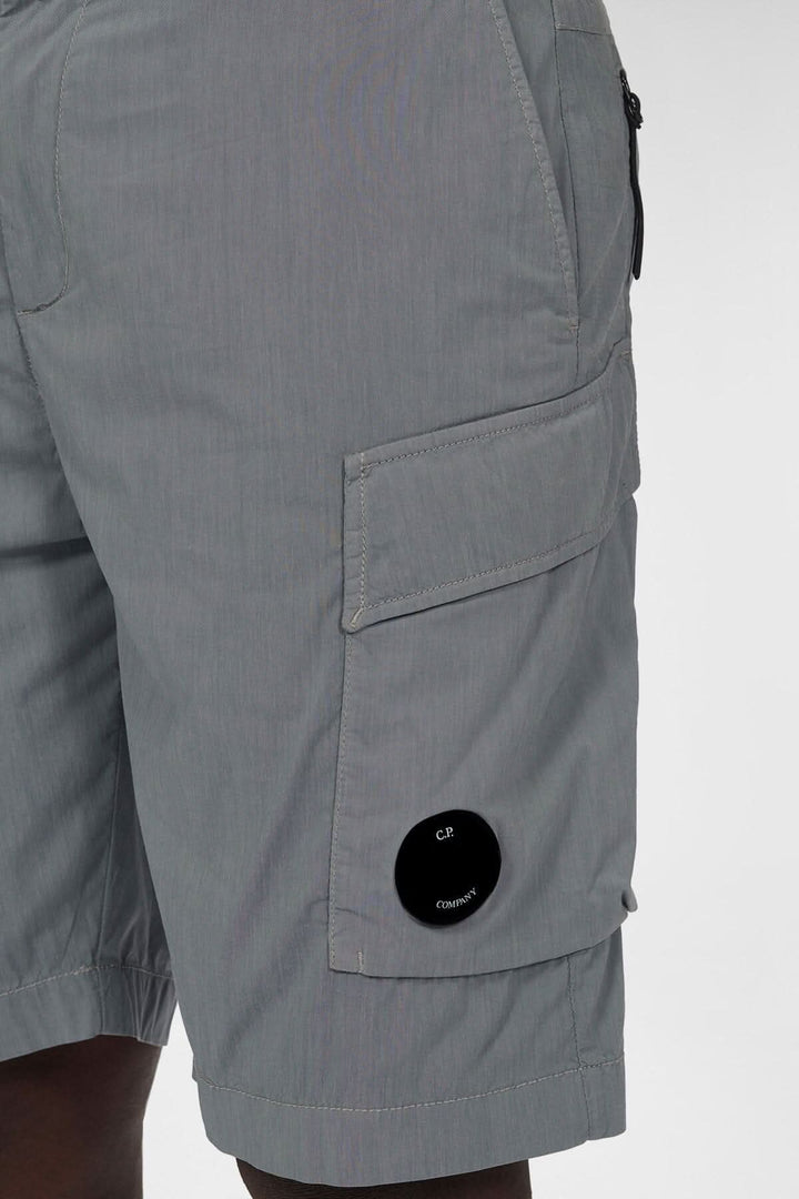 Shorts Cargo Stretch C.P. Company en gris, avec poches latérales et logo emblématique sur le côté.