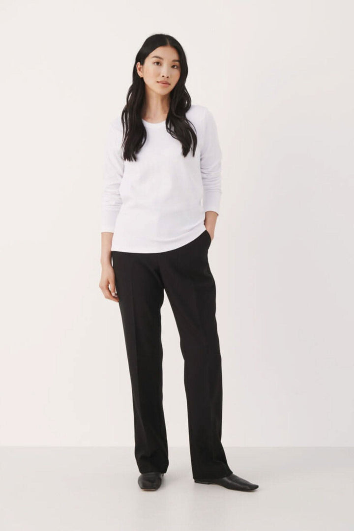 Femme en chandail blanc Refia à manches longues et pantalon noir, présentation de style décontracté.