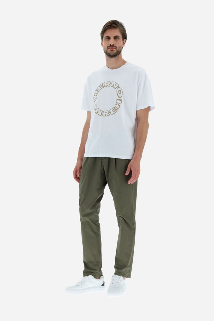 Homme portant un T-shirt HERNO en coton blanc, coupe décontractée, avec logo graphique et pantalon olive.