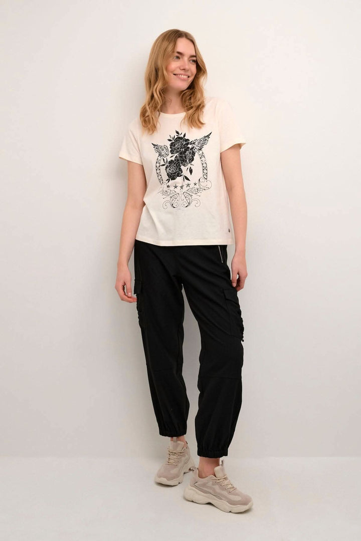 Femme portant un t-shirt Rinne avec imprimé, pantalon noir et chaussures confortables.