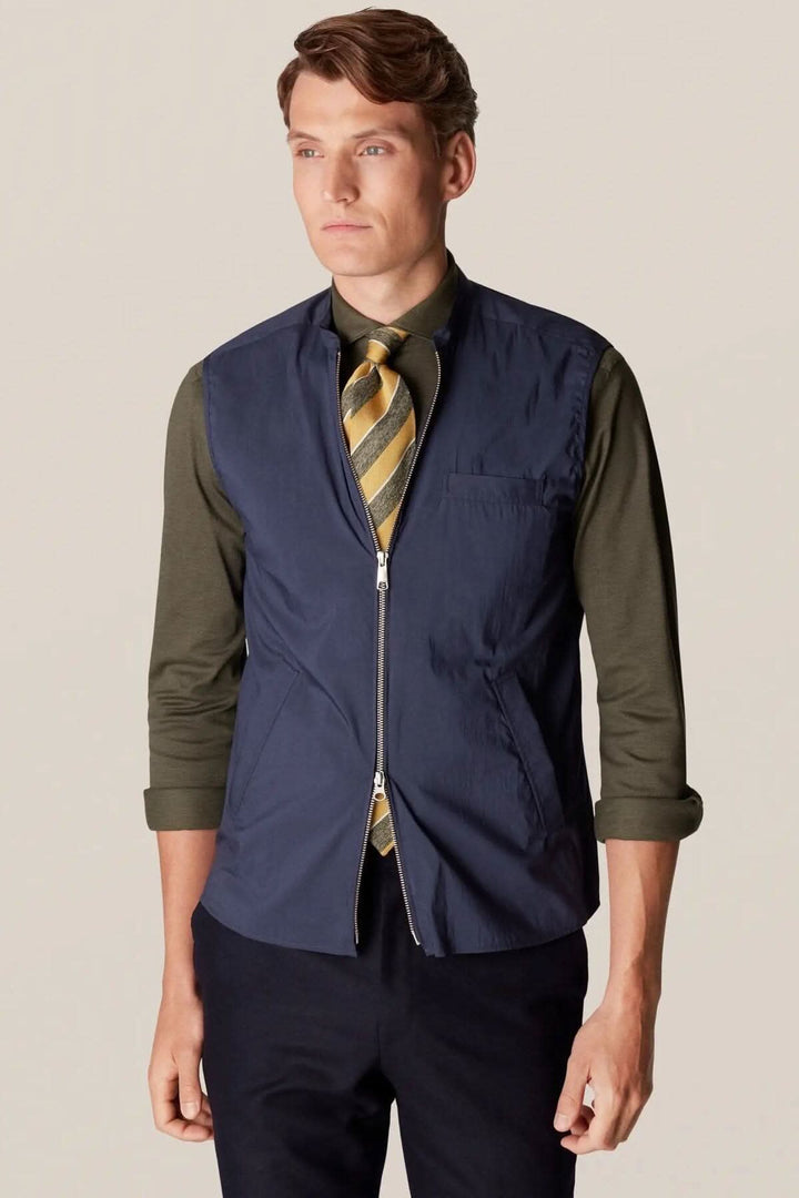 Homme portant une veste sans manches déperlante, élégante et contemporaine, idéale pour la superposition et le style extérieur.