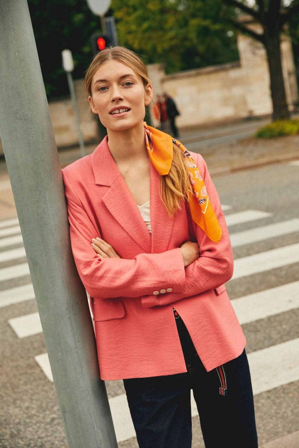 Femme portant un veston rose avec un col classique, posé près d&