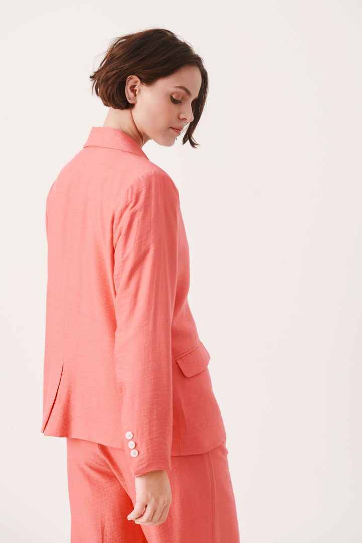 Veston Talena en rose, coupe décontractée avec col classique et boutons, porté avec style.